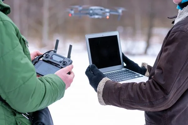 Kaksi henkilöä lennättää dronea