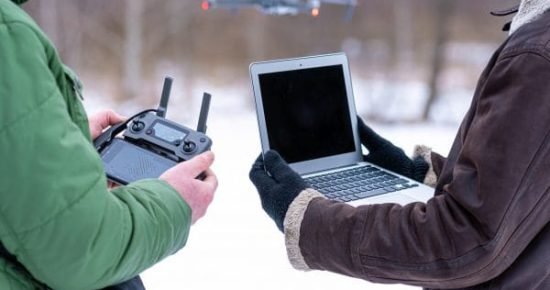 Kaksi henkilöä lennättää dronea Kaksi henkilöä lennättää dronea